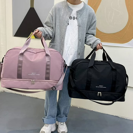 Sacs voyage rose et noir tenus à la main, style sport chic, format cabine avec poignées et bandoulière, pratiques pour déplacement court séjour