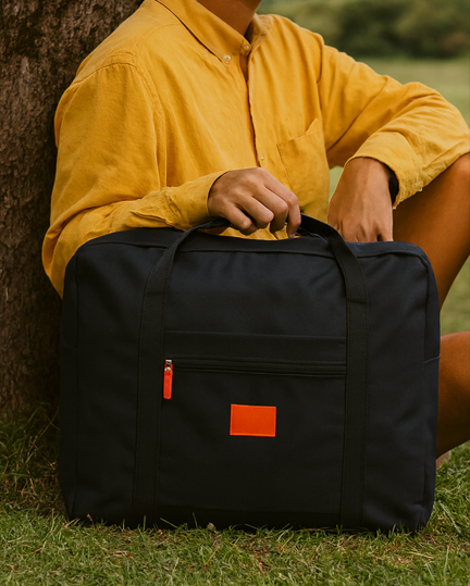 Femme chemise jaune tiens sac de voyage noir sous arbre