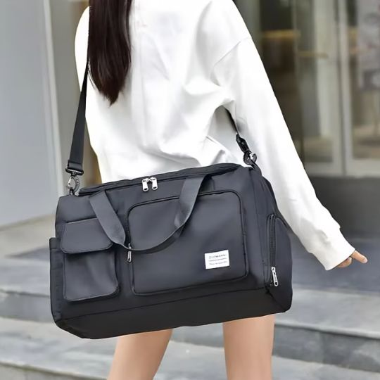 Femme portant un sac de voyage noir en bandoulière, de manière légère, en direction de la salle de sport.