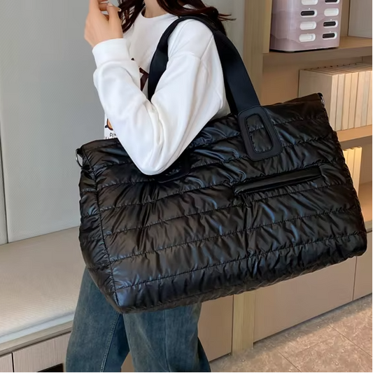 Femme portant un grand sac week end noir matelassé, format spacieux, en marchant