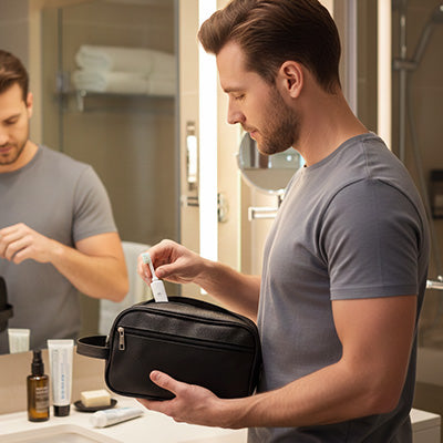 Homme déposant une brosse à dents électrique dans une trousse de toilette  homme effetcuir classique