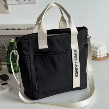 Petit sac week‑end femme noir avec anses beige, posé sur bureau, décor maison tendance