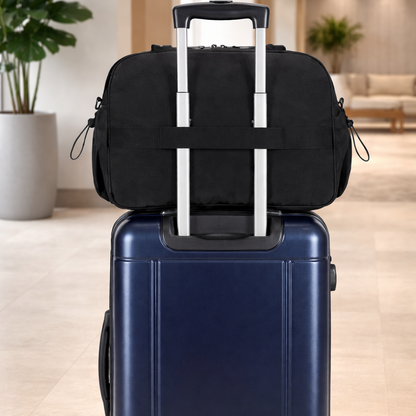 Valise bleu marine avec un sac noir fixé sur sa poignée télescopique. L'ensemble est posé dans un hall d'hôtel moderne, lumineux et épuré avec plantes.