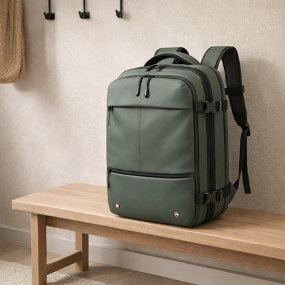 Sac à dos voyage vert, présenté sur un banc en bois dans une entrée, avec système de compression et poches pratiques.