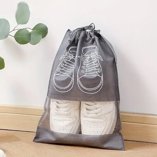 Sac de rangement à chaussures avec des espadrilles blanches prêtes à être rangées dans une valise