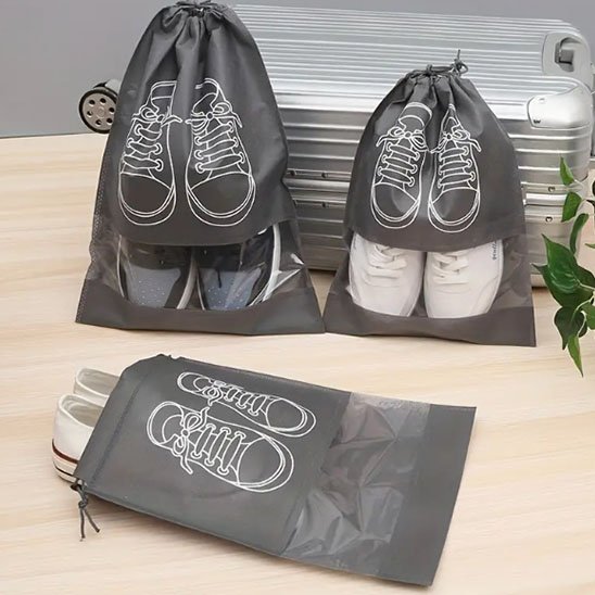 Sac de rangement à chaussures avec des espadrilles sur une table en bois, deux sacs exposés debout sur une valise