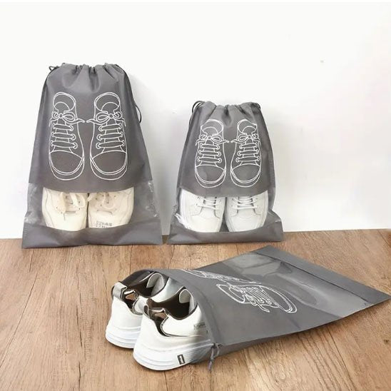 Sac de rangement à chaussures gris avec de grandes espadrilles posées au sol