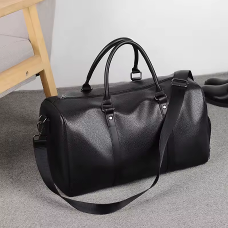 Sac de voyage homme en cuir noir pose au sol, design minimaliste avec anses solides