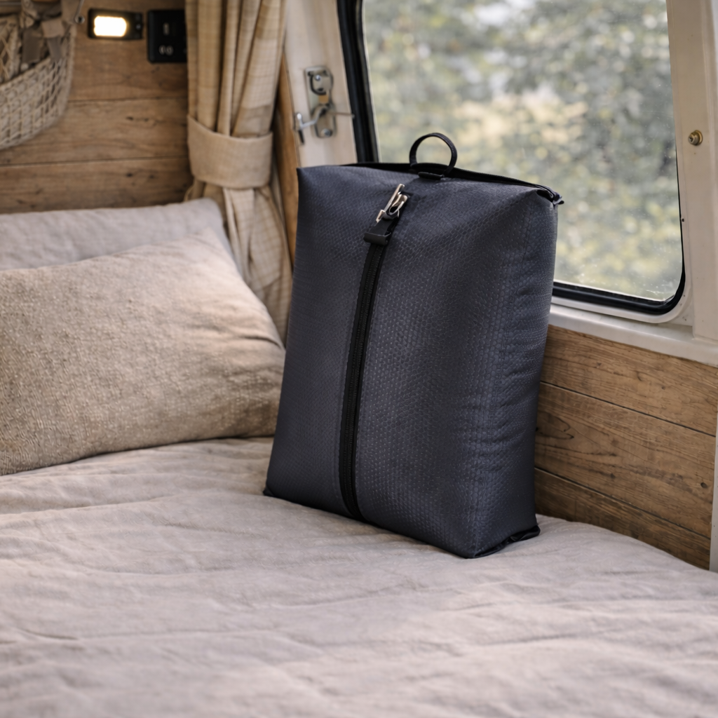 sac sous vide de voyage posé sur lit de van aménagé, housse compacte zippée, gain de place optimal pour ranger vêtements et couettes en road‑trip