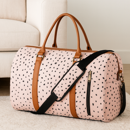 Sac de voyage femme Zen Essentiel rose pâle à taches noires, posé sur un tapis de salon blanc et beige