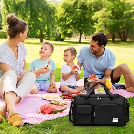 Sac de voyage noir lors d’une sortie en famille pour un pique‑nique dans un beau parc, pendant les vacances estivales.