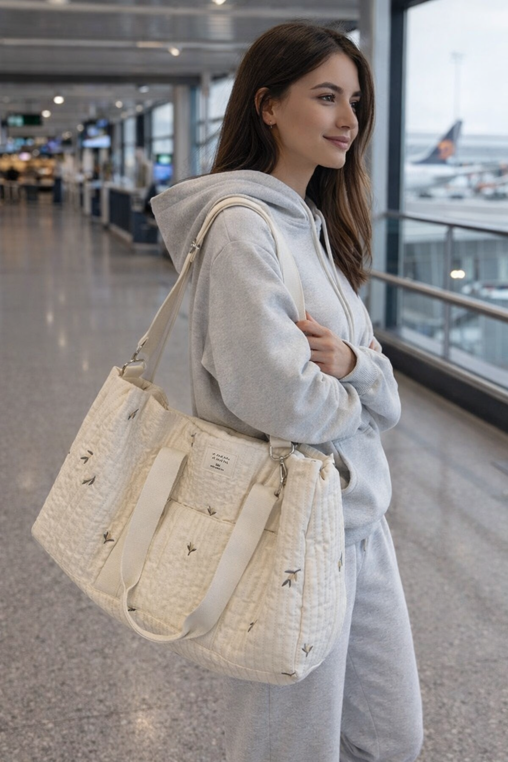 départ pour un voyage en solo. Sac week end en coton matelasse porte à l'épaule par une femme en tenue confortable dans un terminal d aéroport lumineux.