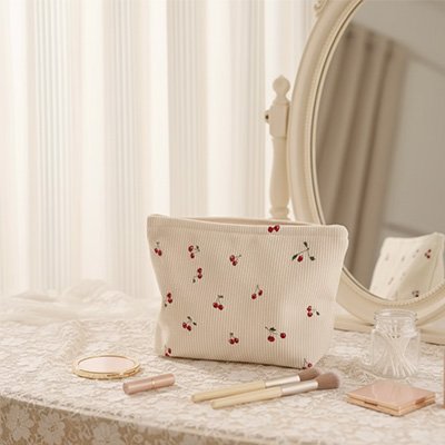 Trousse de maquillage crème à cerises, ouverte sur maquilleuse antique