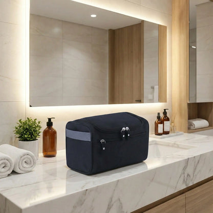 Trousse de voyage noire posée sur un plan de salle de bain moderne, avec fermeture zippée et format compact, idéale pour organiser les essentiels en déplacement.