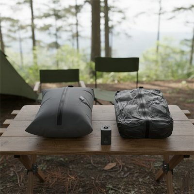 comparaison de sacs sous vide voyage poses sur une table en plein air montrant la difference de volume apres compression avec pompe