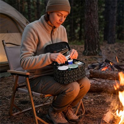 Femme en camping organise ses essentiels dans une trousse de toilette femme noire