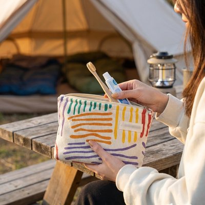 Femme en camping utilise une trousse de toilette colorée