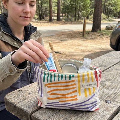 Femme en plein air utilise trousse de toilette posée sur une table en bois 