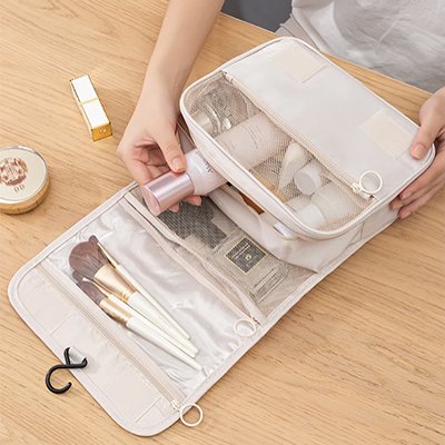 femme prend un produit dans une trousse de toilette de voyage bien organisée