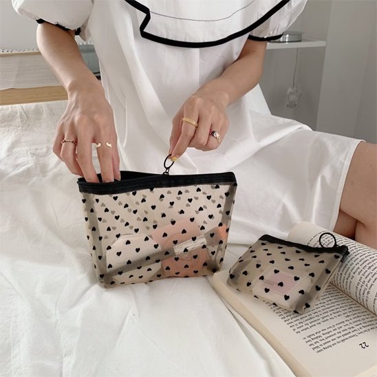 Femme préparant sa pochette de maquillage formats petit et medium sur un lit avant une escapade