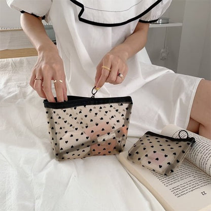 Femme préparant sa pochette de maquillage formats petit et medium sur un lit avant une escapade