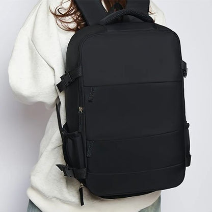 Femme présente le sac à dos de voyage noir pour démontrer sa capacité de rangement et les 2 pochettes sur le dessus