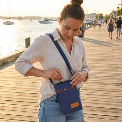 Femme sur un quai range ses essentiels dans un sac à bandoulière bleu