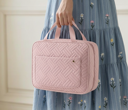 Femme tenant une trousse de toilette femme rétro rose, design matelassé élégant, format pratique pour déplacements et week-ends.