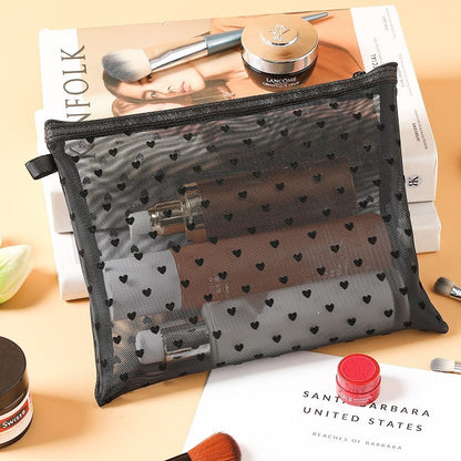 Grande pochette de maquillage noire, posée sur une table de nuit en bois