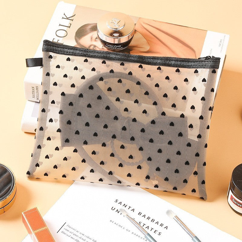 Grande pochette de maquillage blanche, posée sur une table de nuit en bois