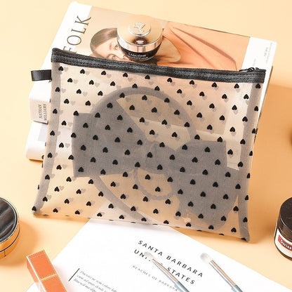 Grande pochette de maquillage blanche, posée sur une table de nuit en bois