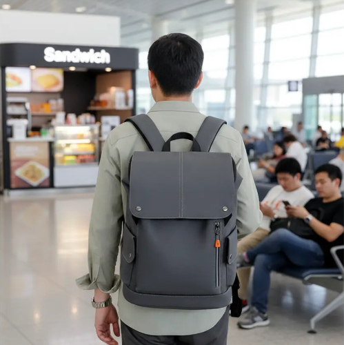 Homme de dos à l’aéroport portant un sac à dos voyage aux dimensions EasyJet, gris, format cabine, devant la zone d’embarquement