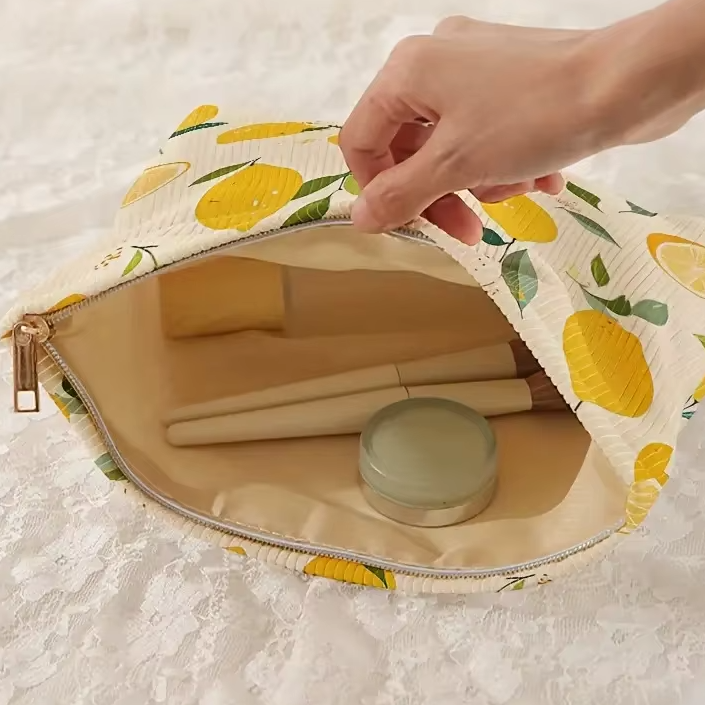 main ouvrant une trousse de maquillage à motifs citrons