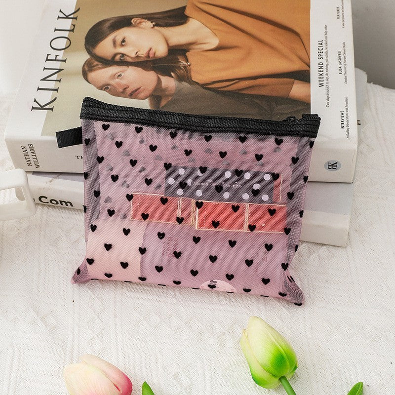 Moyenne pochette de maquillage rose, posée sur une table de nuit blanche
