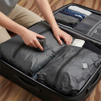 personne rangeant une valise ouverte en utilisant un sac sous vide voyage pour compresser les vetements et optimiser l espace dans les bagages