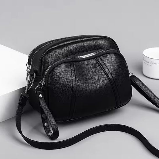 Petit sac à bandoulière femme noir sur table grise