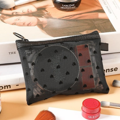 Petite pochette de maquillage noire, posée sur une table de nuit en bois