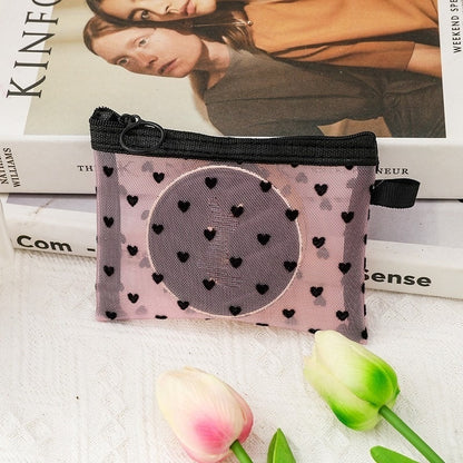 Petite pochette de maquillage rose, posée sur une table de nuit blanche