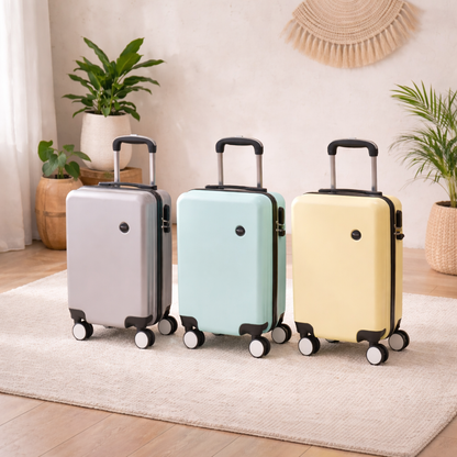 Petite valise aux dimensions Ryanair — grise, bleue et jaune — présentées dans un salon zen sur un tapis avec des plantes.