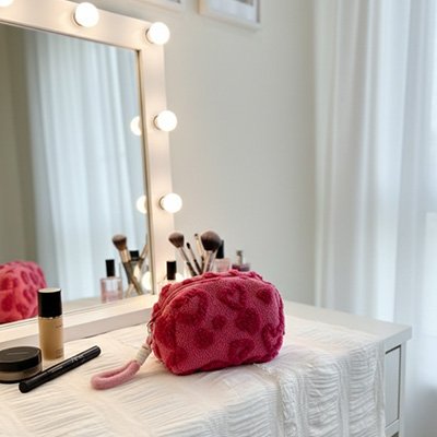 Pochette maquillage fuchsia en tissu texturé sur coiffeuse