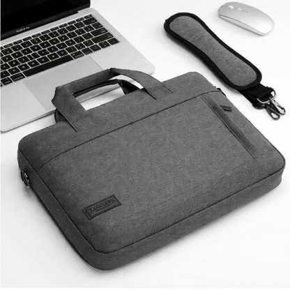 Pochette ordinateur grise avec bandoulière posée près d’un ordinateur et d’une souris.