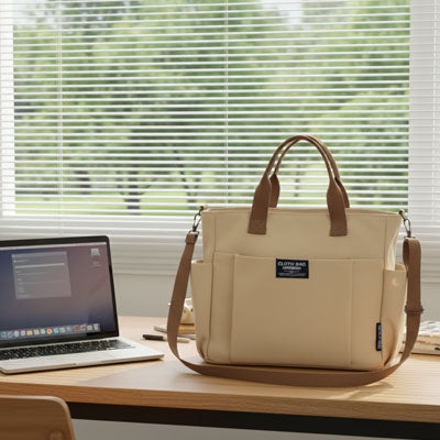 Pochette ordinateur pour femme beige kaki posée sur un bureau à côté d’un ordinateur portable dans un espace de travail lumineux.