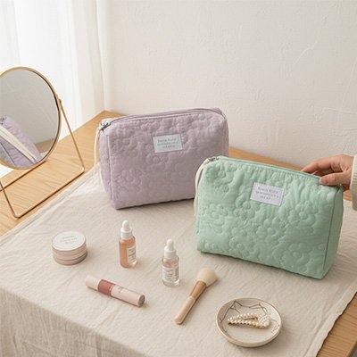 Présentation de la magnifique trousse à maquillage en deux couleur , verte et lilas, sur belle maquilleuse en bois blanc