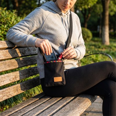 Sac à bandoulière femme noir, porté en travers du corps sur un banc