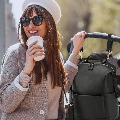 femme savourant un café avec un grand sourire, son sac à dos de voyage fixé sur la poussette, une scène zen et raffinée qui évoque confort, organisation et art de vivre en mouvement