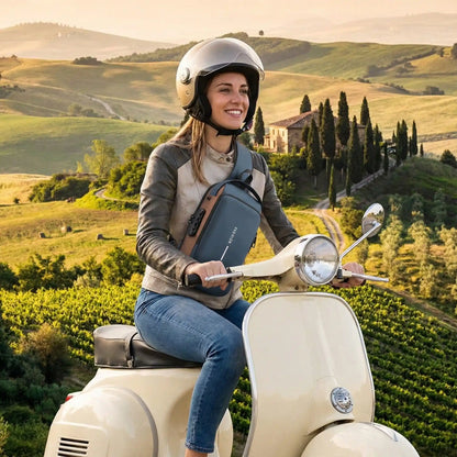 Sac à dos de voyage zenantivol bleu porté en bandoulière par une femme sur une Vespa crème en Toscane, ambiance lifestyle scooter voyage.