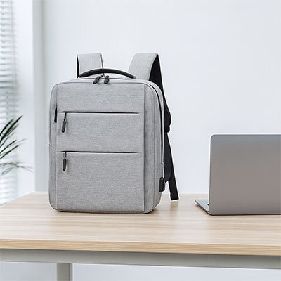 Sac à dos ordinateur élégant avec compartiments zippés, présenté dans un environnement de bureau lumineux, pensé pour le transport sécurisé d’un PC portable.