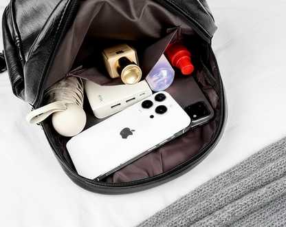 sac à dos voyage sur lit et couverture de laine ouvert contenant téléphone, batterie externe et produits essentiels. Permet de voir un rangement organisé et pratique pour le voyage.