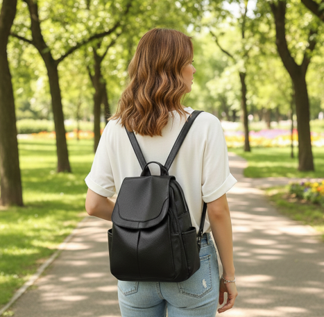 Sac à dos voyage noir porté par une femme marchant dans un parc, au style urbain et décontracté. Idéal pour les déplacements quotidiens et les voyages légers.