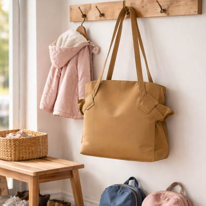 Sac de voyage femme beige élégant accroché sur porte-manteau dans une entrée de maison, style pratique pour voyage et quotidien.